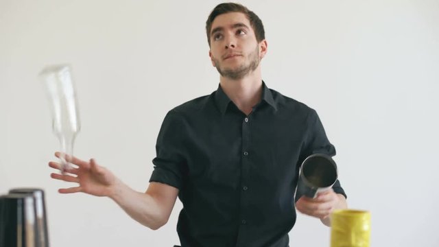 Professinal bartender man juggling bottles and shaking cocktail at mobile bar table on white background