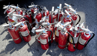 Building's wall mounted fire extinguishers collected on sidewalk for periodic inspection and...