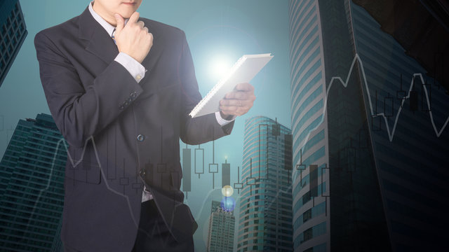 Double exposure of businessman using tablet with financial graph chart and building background.