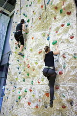 young sporty girls practicing rock-climbing on a rock wall indoors