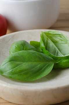 Whole Basil Leaves in close with Tomato in Background
