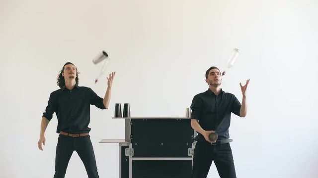 Professinal bartender men juggling bottles and shaking cocktail at mobile bar table on white background