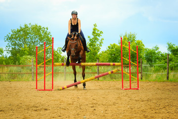 Jockey young girl doing horse jumping through hurdle