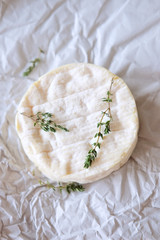 Brie cheese on wrapping paper with thyme herbs