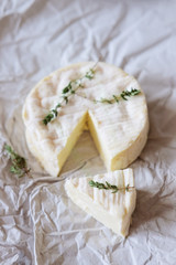 Brie cheese on wrapping paper with thyme herbs