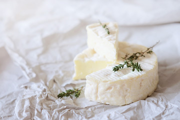 Brie cheese on wrapping paper with thyme herbs