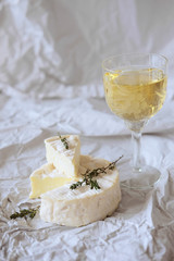 Brie cheese on wrapping paper with thyme herbs