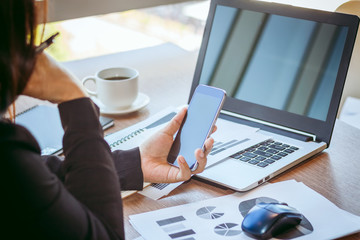 Close Up businessmen working at a coffee shop with a document with a smartphone and a laptop computer.