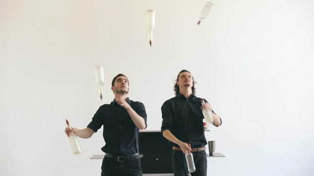 Professinal bartender men juggling bottles and shaking cocktail at mobile bar table on white background