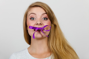 Blonde woman biting decorative purple bow