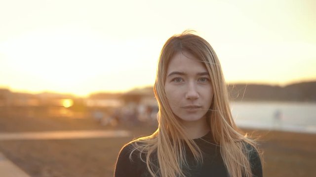 Smiling Blond Girl is Walking on Field at Sunset