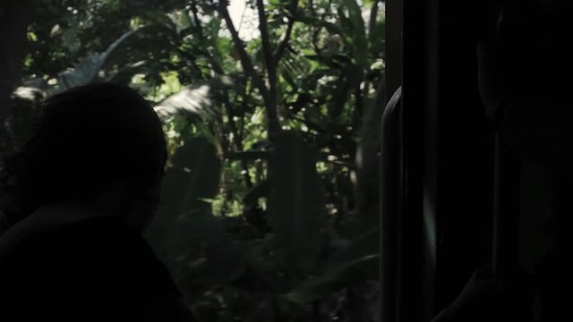Young woman traveling by train in Sri Lanka, seat, no doors, jungle background