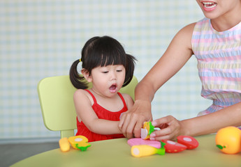 Asian Child girl and mother playing plastic fruits at the Kid room