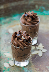 Chocolate mousse with chocolate sauce and almond slices in a glasses on a vintage background.