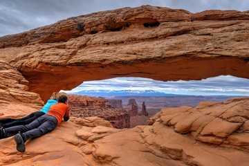 Friends enjoying the view of canyon and mountains. Mesa Arch. Canyonlands National Park. Moab....