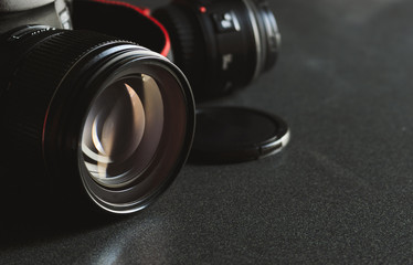closeup digital camera on black wooden table with soft-focus in the background. over light 