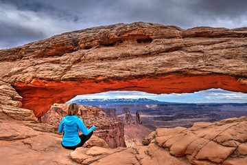 Woman meditating by sandstone arch. Canyonlands  Natonal Park. Moab. Utah. United States. 