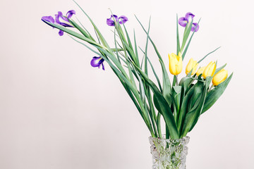 Fototapeta na wymiar Yellow and purple flowers in a vase on a beige background