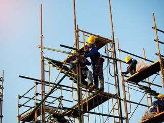 Construction workers working on scaffolding, Man Working on the Working at height with blue sky at construction site