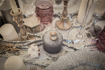 Wedding rings on a candle. Decorations sprinkled with snow.