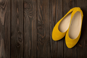 Yellow women's shoes (ballerinas) on wooden background.