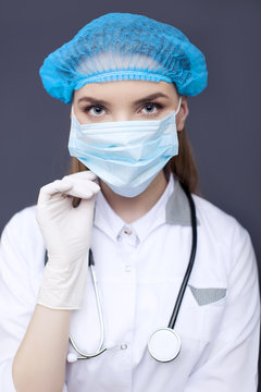 
Face of woman  doctor, nurse  in mask and haircap,  with stethoscope. 
