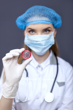 
Woman doctor, nurse in mask  with condom on palm. Conceptual image 
