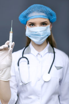 
Blurred figure of  woman doctor, nurse in  mask with Injection syringe
