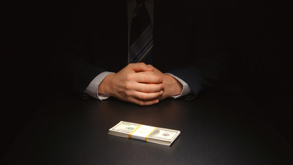 BRIBE: Businessman waits and puts a money on a table (US dollar)