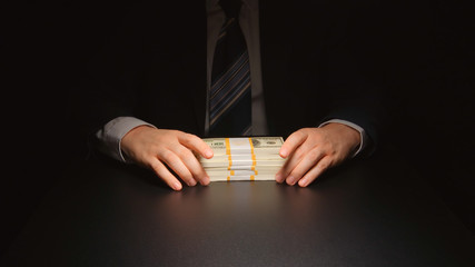 BRIBE: Businessman touches a money bundle on a table
