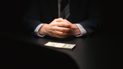 BRIBE: Businessman waits and puts a money on a table (US dollar) - two person