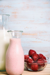 strawberry smoothie or milkshake in retro bottle, milk and frozen strawberries with old, shabby chic, blue wooden background  with copy space 