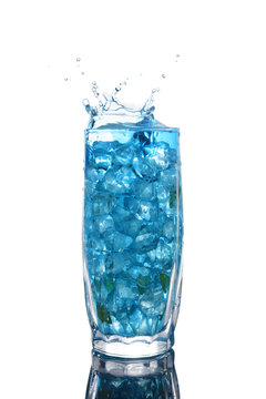 Glass of a blue alcoholic cocktail drink with ice and mint