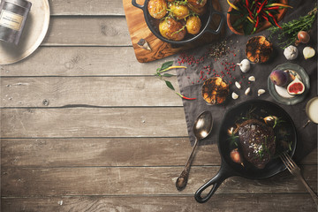 Overhead view of colorful roast vegetables, savory sauces and salt served with grilled t-bone steak on a rustic wooden counter in a country steakhouse created digital illustration - 139653910
