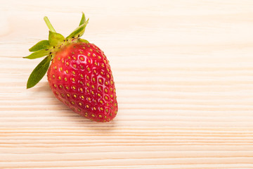 One red strawberry on the edge of the table