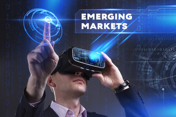 Business, Technology, Internet and network concept. Young businessman working in virtual reality glasses sees the inscription: Emerging markets