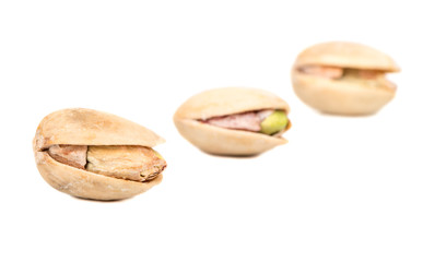 Fototapeta premium Three salted pistachio nuts on white background