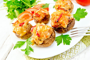 Champignons stuffed with meat and peppers in plate on light board