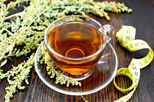 Tea with wormwood in glass cup and meter on board