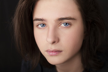 A portrait of a handsome blue eyes teenager on dark background