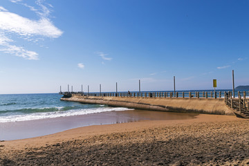 Beach Sea and Concrerte Pier Extending into Ocean