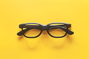 Black sunglasses or eyeglasses on a yellow background