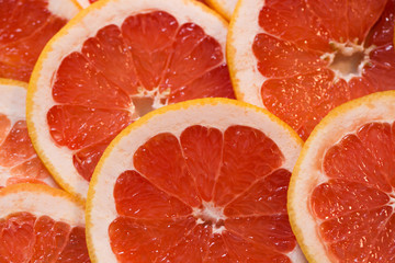 Bright red background with juicy slices of grapefruit. Healthy food background.