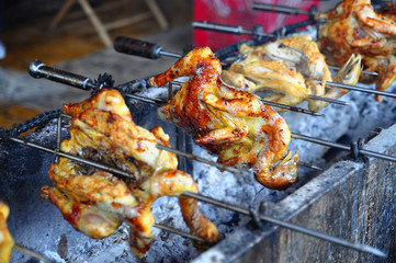 Grilling whole chicken on hot charcoal in asia