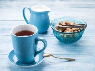 Fotobehang Cup of tea, milk jug and cane sugar cubes. © volff