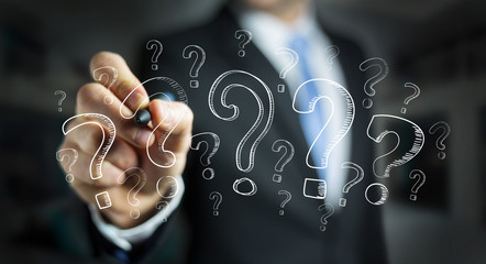 Businessman drawing question marks with a pen