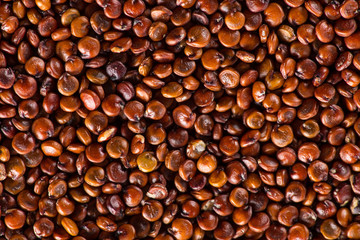 Red quinoa seeds on white wooden table.