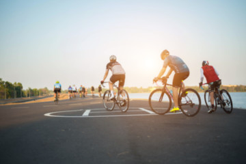 Fototapeta na wymiar The cyclists blurred photo on road background on sunset