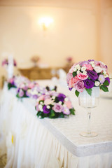 A bouquet of flowers in a glass vase on a wedding table