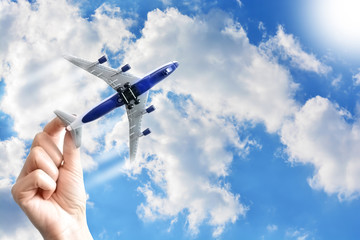 Airplane model in woman hand flying under the blue sky